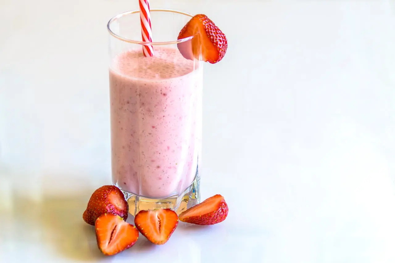 A clear glass containing a thick A clear glass containing a thick smoothie. The glass is garnished with strawberries.